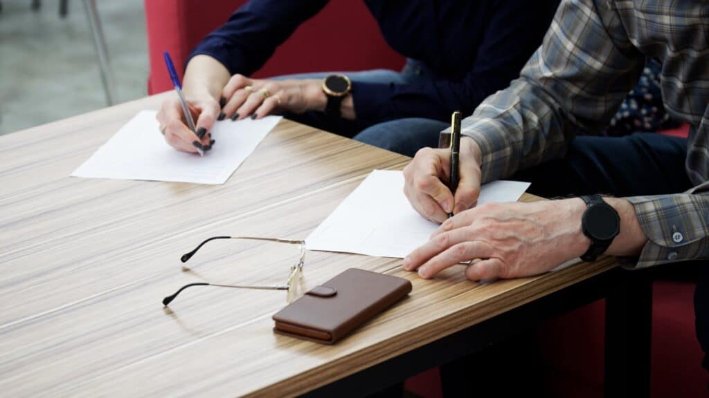 Woman and man sitting at table filling out documents