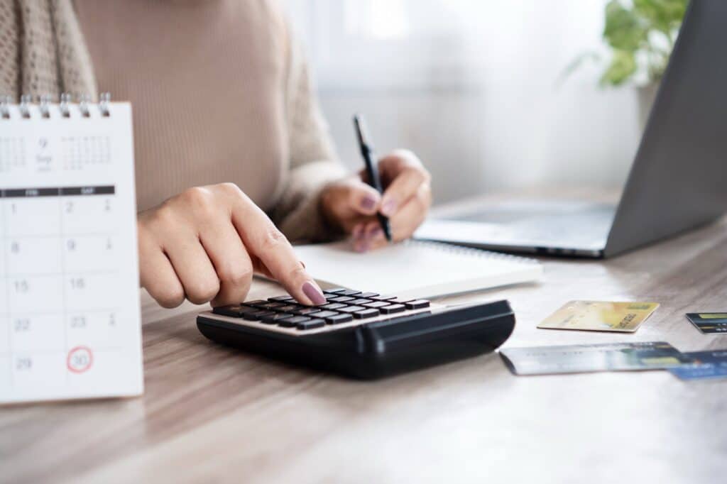 A table with a calendar, a calculator, laptop, and credit cards