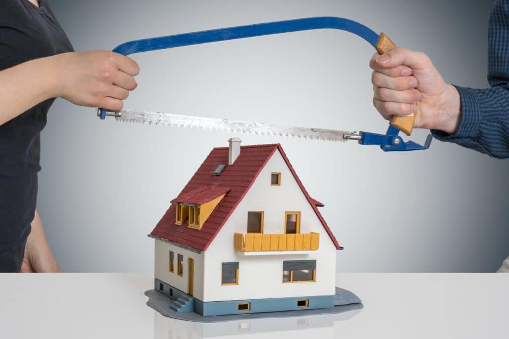 Two people holding a saw to a wooden house