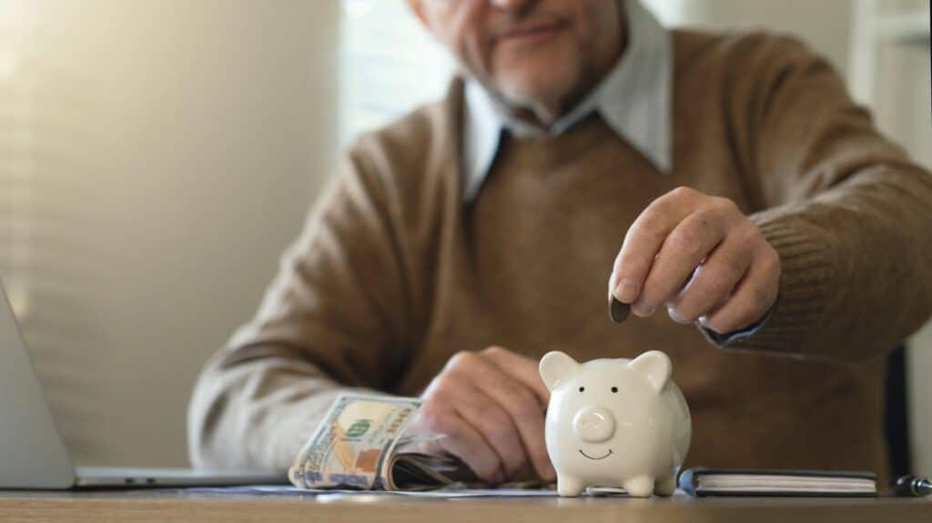 Man putting change and follow bills into his piggy bank