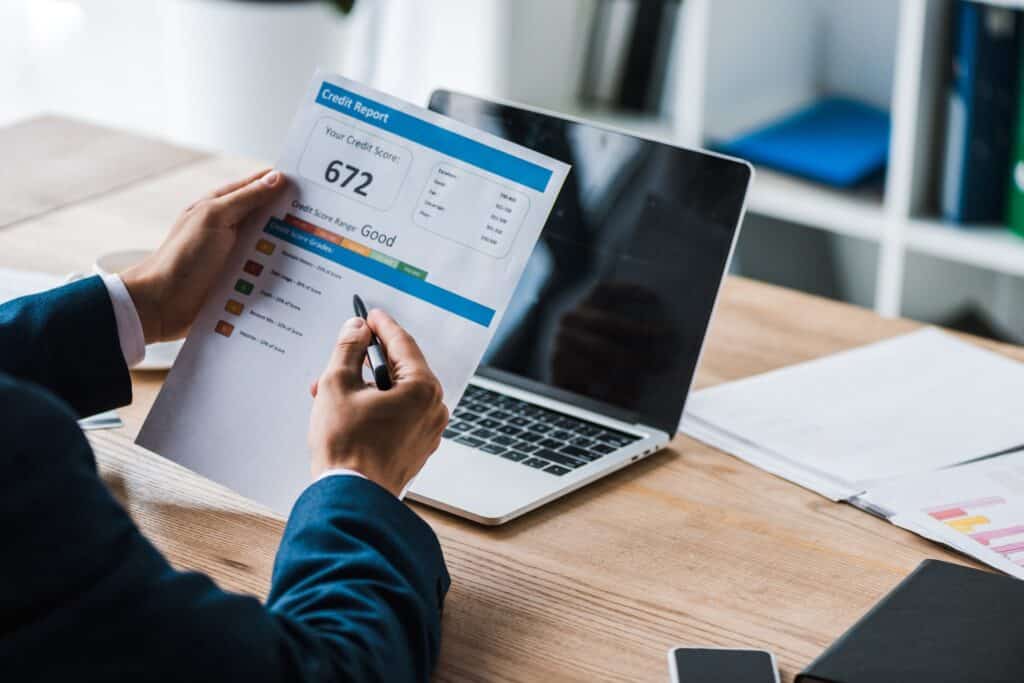 A man with a pen sitting at a desk point at a printout of a credit report.