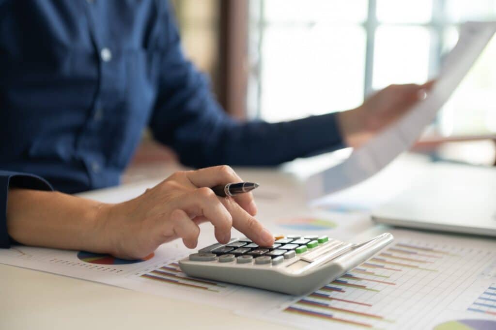 Person holding paperwork and a pen and using a calculator