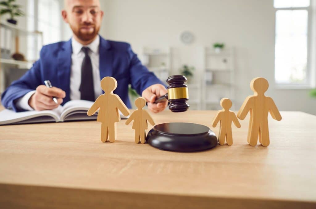 Young male holding a gavel and pen writing in a notebook with a wooden family separated by the gavel