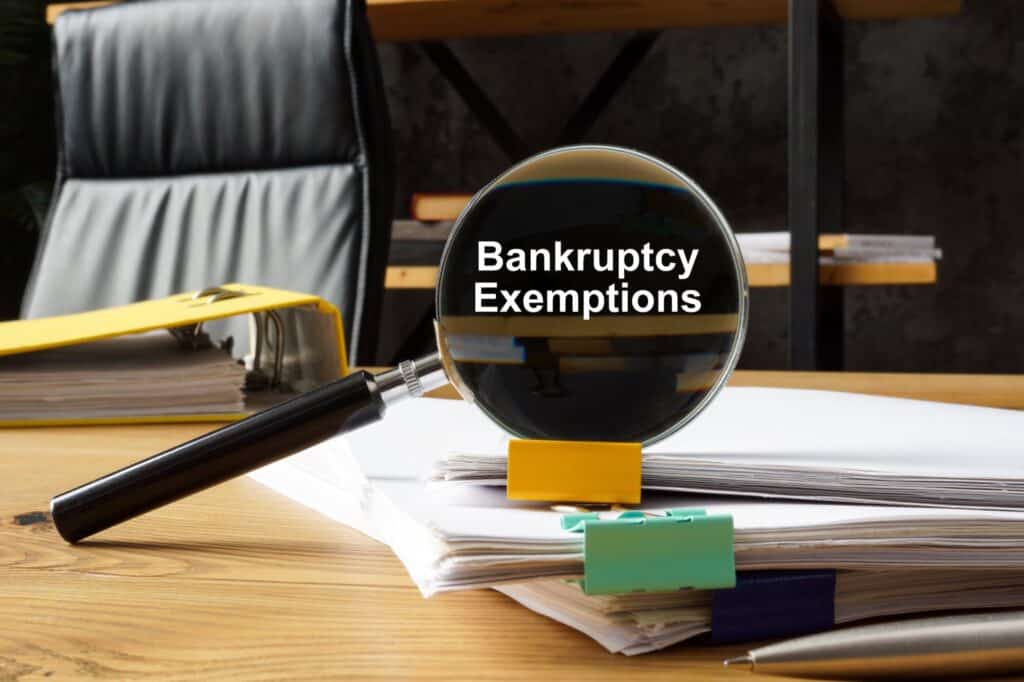 Magnifying glass with the words bankruptcy exemptions in it on top of a stack of papers