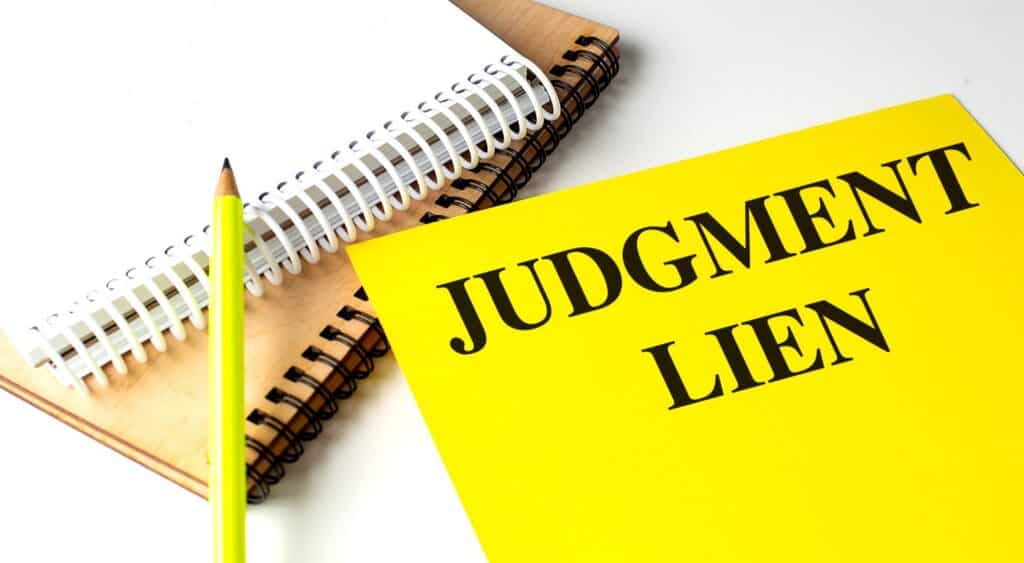 Judgement Lien on a yellow piece of paper next to a yellow pencil and notebooks